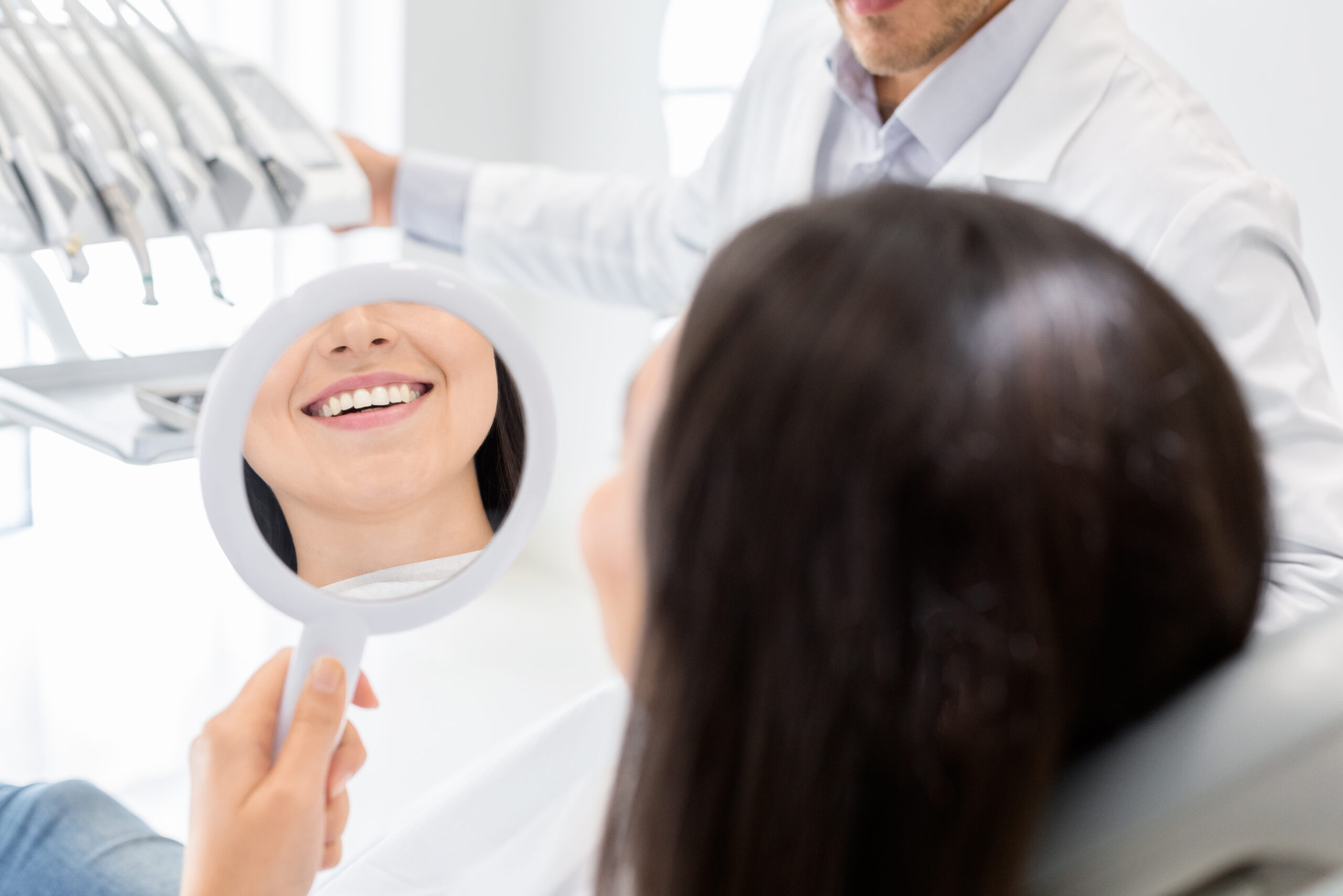 Happy female patient looking at her smile in a mirror at CFD
